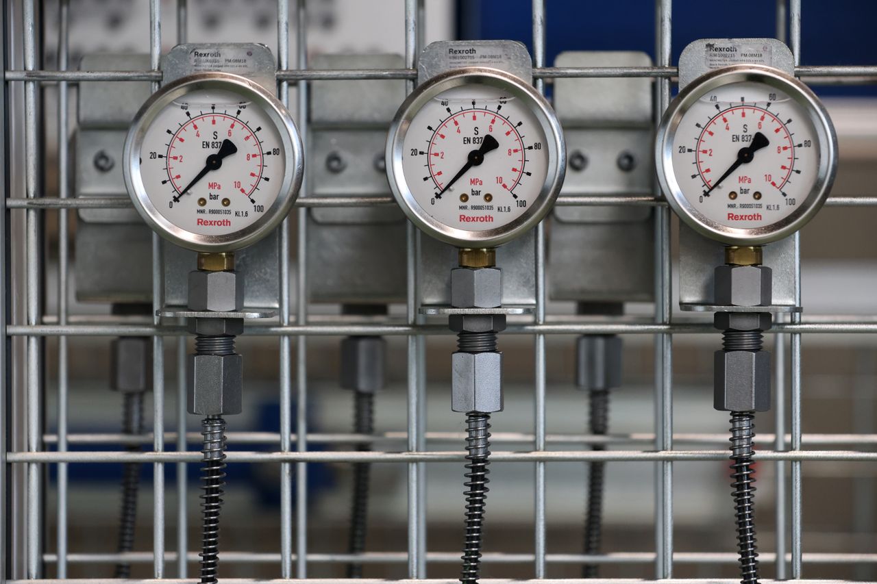 Close-up of industrial pressure gauges mounted on a metal grid in a factory setting.